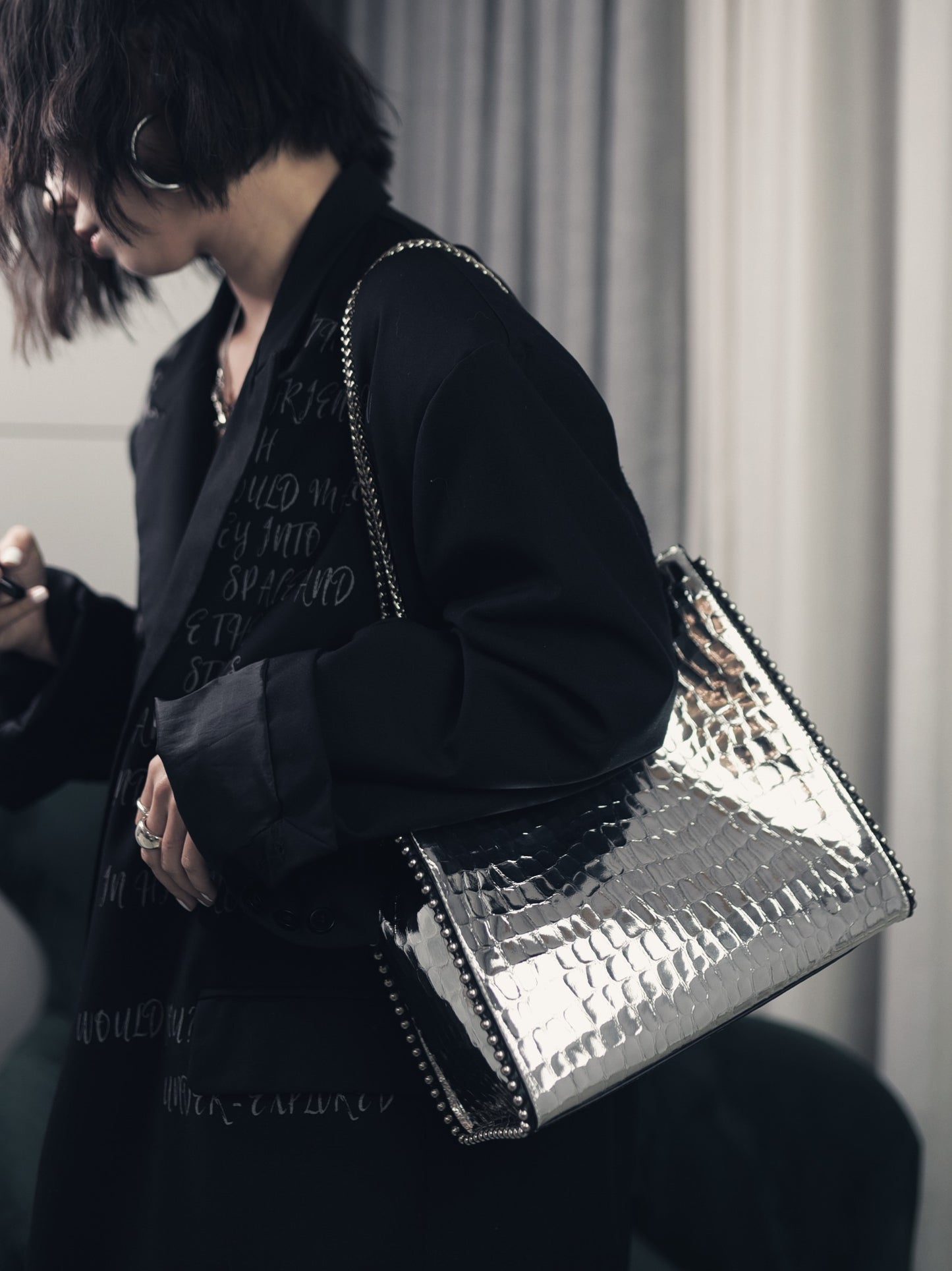 Person holding a shiny black handbag with a blurred background